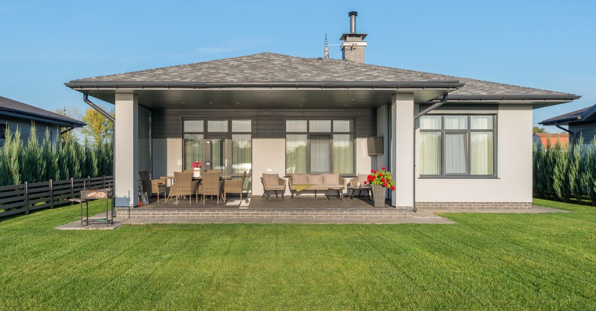 Contemporary house exterior with a large backyard patio and manicured lawn.